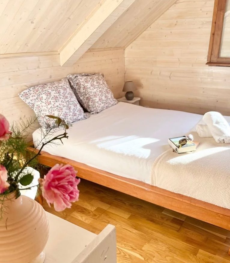 Chambre aux draps blancs et coussins fleuris